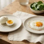 Boiled egg vs fried egg arranged side by side on a natural table for a simple cooking method comparison.